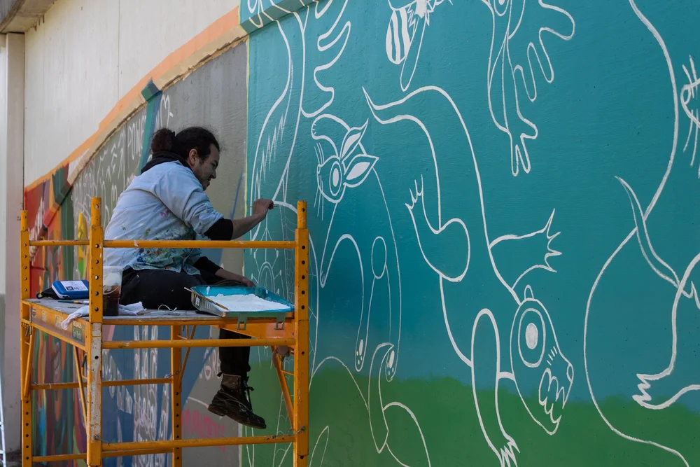 A person creating a mural on the side of a building